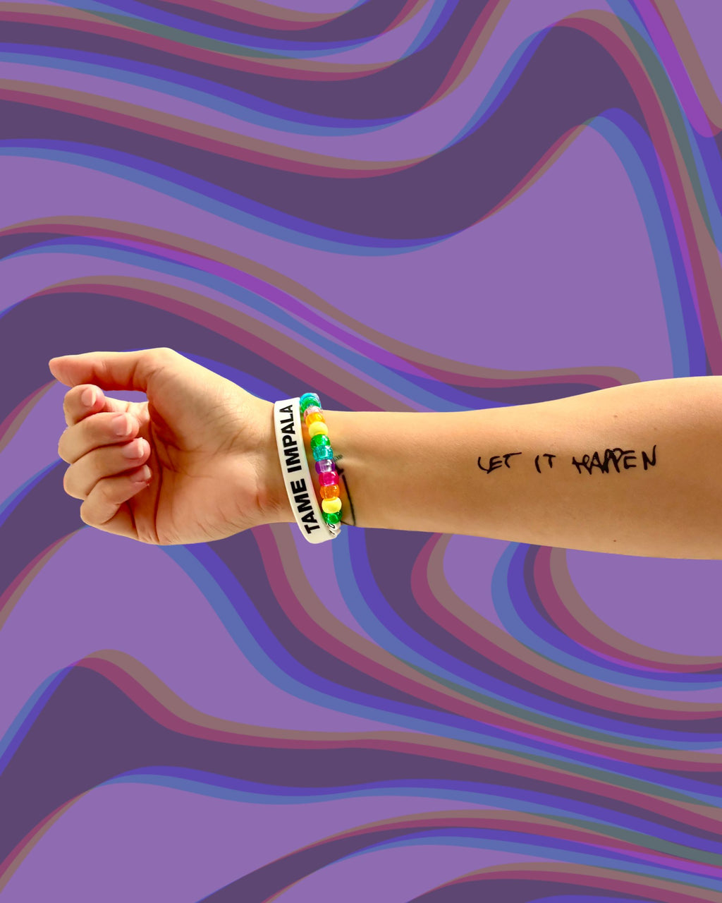 Model wearing a "Let it Happen" temporary tattoo on arm with a colorful bracelet on a multicolored wavy background