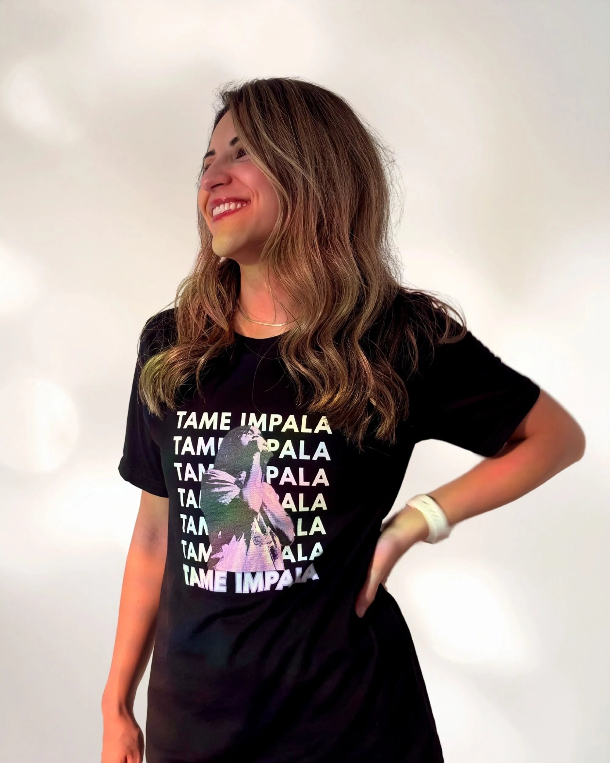 Woman wearing a black t-shirt with 'Tame Impala' text design and a photo of Kevin Parker with a purple filter